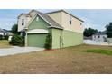 A view of the green two car garage, green siding, and well maintained lawn and landscaping at 807 Glen Creek Ct, Fruitland Park, FL 34731