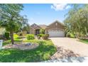 Well-maintained single-story home with lush landscaping, a brick driveway, and a two-car garage, offering comfortable living at 8632 Sw 86Th Cir, Ocala, FL 34481