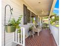Charming front porch with brick flooring and white railing, furnished with a bench and decorated with hanging plants at 10989 Sw 86Th Ave, Ocala, FL 34481