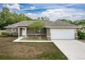 Attractive home showcasing a neatly paved driveway leading to an attached two-car garage, with a well-kept lawn and neutral exterior at 13645 Se 42 Ave, Summerfield, FL 34491