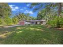 Cozy home with lush green lawn surrounded by mature trees providing shade, complete with attached garage at 16571 Se 95Th Street Rd, Ocklawaha, FL 32179