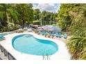 Relaxing kidney-shaped pool with lounge chairs overlooking the lake and verdant natural landscaping at 20800 River Dr # A11, Dunnellon, FL 34431