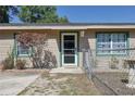 Tan home with a green trim, front door with a glass screen, a tree and a fenced in area with a concrete slab in front at 2808 Ne 24Th Ct, Ocala, FL 34470