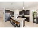 Modern kitchen with granite countertops, dark cabinetry and seating for four at the kitchen island at 8090 Penrose Pl, Wildwood, FL 34785