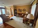 Cozy living room with plush seating, a decorative cabinet, and natural light from the window at 12453 Se 93Rd Court Rd, Summerfield, FL 34491