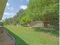 Lush backyard featuring a well-maintained lawn, mature trees, and a wooden fence for added privacy at 13196 Se 86Th Cir, Summerfield, FL 34491
