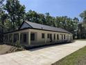Side angle of the home featuring a large porch, long driveway, and lush green trees at 18890 Sw 60Th St, Dunnellon, FL 34432