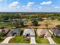 An aerial view of homes on a golf course showcasing mature landscaping under a partly cloudy blue sky at 2008 Palo Alto Ave, The Villages, FL 32159
