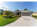 Landscaped home featuring a decorative driveway, a two-car garage, and mature palm trees at 2008 Palo Alto Ave, The Villages, FL 32159