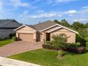 Inviting single-story home with a brick driveway, attached two-car garage, and lush green lawn at 3587 Nw 55Th Cir, Ocala, FL 34482