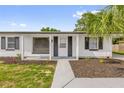 Inviting white home exterior showcasing a cozy covered entryway, lush landscaping, and modern black accents at 3807 Sw 143Rd Lane Rd, Ocala, FL 34473