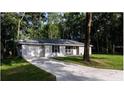 Inviting single-story home featuring a long driveway and attached garage, nestled in a wooded area at 6432 Nw 64Th Ter, Ocala, FL 34482
