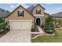 Charming two-story home featuring a brick driveway, manicured lawn, and stone accents on the facade at 6816 Sw 95Th Cir, Ocala, FL 34481