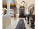Grand foyer with a decorative mirror, tile flooring, soaring columns, and a beautiful front door at 2146 Se 25Th Loop, Ocala, FL 34471