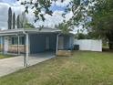 View of the backyard area with a white fence and covered carport at 21570 Sw Raintree St, Dunnellon, FL 34431