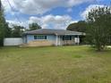 A quaint single-story home with a light blue exterior and a manicured lawn at 21570 Sw Raintree St, Dunnellon, FL 34431
