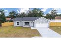 Single-story home featuring a two-car garage, a well-maintained lawn and a wooden fence at 28 Olive Dr, Ocala, FL 34472