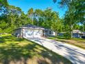 Exterior view of home featuring a lush green lawn, long driveway, two-car garage, and a welcoming front porch at 5092 Sw 197Th Ter, Dunnellon, FL 34431