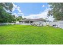 A spacious backyard featuring lush green grass, a white picket fence, and a covered patio at 9 Fir Trail Pass, Ocala, FL 34472