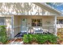 Inviting front porch featuring a white wicker bench with blue cushions and well-maintained landscaping at 9726 Sw 94Th Ter # C, Ocala, FL 34481