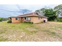View of the home's rear exterior, showcasing the attached garage, siding, and backyard at 10631 W Highway 40, Ocala, FL 34482