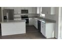 Kitchen featuring white cabinets, stainless steel appliances and gray countertops at 2871 Se 145 Pl, Summerfield, FL 34491