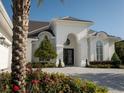 Beautiful white home with a dark roof and brick driveway, complemented by colorful flowers and lush greenery at 7585 Nw 33Rd Pl, Ocala, FL 34482