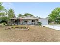 Single-story home with a covered front porch, a small garden, and an attached garage at 9940 Sw 103Rd Pl, Ocala, FL 34481