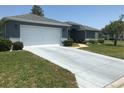 Home with a freshly painted driveway, manicured lawn, and neat landscaping at 11411 Sw 138Th Ln, Dunnellon, FL 34432