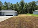 A single-story home with a two-car garage sits to the left of large grass lawn at 19660 Sw 59Th Ln, Dunnellon, FL 34431