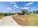 A well-kept lawn with mature trees, and an inviting driveway leads to a charming brick home with a brown roof at 2045 Se 32Nd St, Ocala, FL 34471