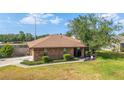 A brick house features a well-kept lawn, mature trees, and an inviting driveway on a bright, sunny day at 2045 Se 32Nd St, Ocala, FL 34471