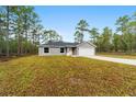 Well-maintained single-story home with gray stucco, a white garage door, and manicured front lawn at 24375 Nw Foxglove Ln, Dunnellon, FL 34431