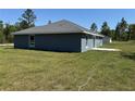 Back view of a single-story home surrounded by a spacious grassy yard and natural landscapes at 4424 Sw Viola Ct, Dunnellon, FL 34431