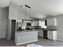 Bright kitchen featuring white cabinets, stainless steel appliances, granite countertops, and modern pendant lighting at 4424 Sw Viola Ct, Dunnellon, FL 34431
