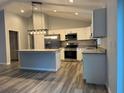 Bright kitchen features stainless appliances, a center island, gray cabinets and granite countertops at 4424 Sw Viola Ct, Dunnellon, FL 34431