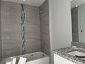Bathroom featuring a shower-tub combo with decorative accent tiles, a granite vanity top, and modern fixtures at 4928 Sw Evergreen Ct, Dunnellon, FL 34431