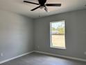 Bedroom with a ceiling fan, wood-look tile flooring, neutral walls, and a window overlooking the yard at 4928 Sw Evergreen Ct, Dunnellon, FL 34431