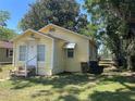 Cozy yellow cottage with white trim, steps, and a partially shaded yard at 621 Ne 20Th St, Ocala, FL 34470