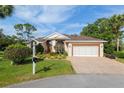 Charming single-story home with a manicured lawn, brick driveway, and a two-car garage at 6882 Sw 113Th Pl, Ocala, FL 34476