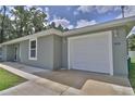 Attached one-car garage with a white door and gray exterior and well-maintained landscaping at 838 Nw 124Th Street, Citra, FL 32113