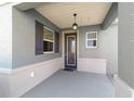 View of a covered front porch with decorative hanging light fixture and textured walls at 8693 Sw 76Th Ln, Ocala, FL 34481
