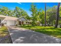 Inviting home showcasing a long driveway and a lush green lawn, framed by mature trees and landscaping at 8747 Sw 98Th Street Rd # F, Ocala, FL 34481