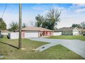 Well-maintained home featuring a long driveway, two-car garage, lush lawn, and fenced yard at 13425 Sw 106Th Pl, Dunnellon, FL 34432