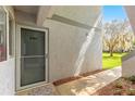 Exterior view of a unit entrance with a screen door, small welcome mat, and view of greenery at 450 Fairways Cir # A101, Ocala, FL 34472