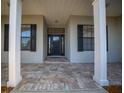Covered porch with stone flooring and decorative front door with sidelights at 4735 Se 35Th St, Ocala, FL 34480