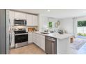 Bright kitchen featuring stainless steel appliances, white cabinets and quartz countertops, with view to the living area at 8413 Gower Trl, Wildwood, FL 34785