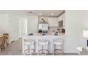 A modern kitchen featuring white cabinetry, stainless steel appliances, and bar seating and dining area at 8415 Gower Trl, Wildwood, FL 34785
