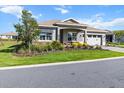 Attractive home showcasing a well-manicured lawn, lush landscaping, and a paved driveway at 10327 Sw 96Th Loop, Ocala, FL 34481