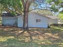 Back exterior of light blue home with green lawn and a mature tree providing shade at 11025 Sw 64Th Ave, Ocala, FL 34476